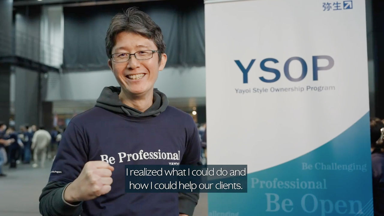 A smiling employee standing in front of a banner that reads "YSOP, Yayoi Style Ownership Program".