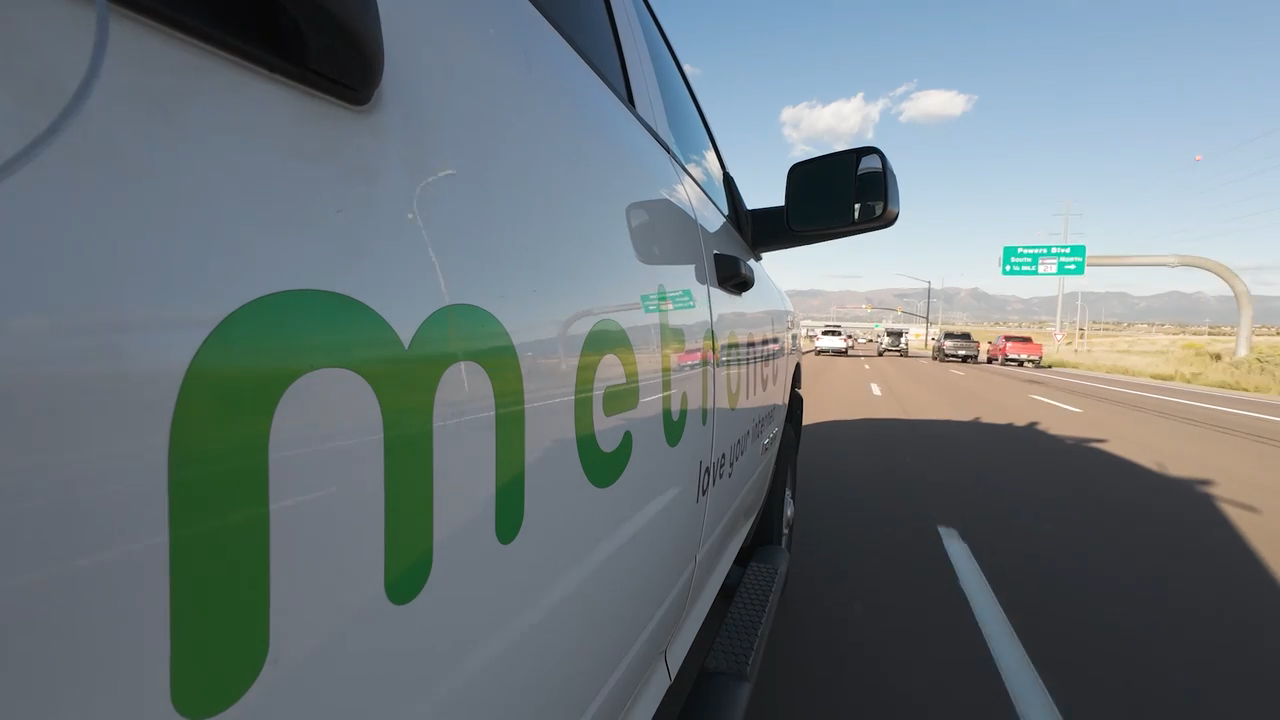 The Metronet logo on the side of a truck driving down the highway.